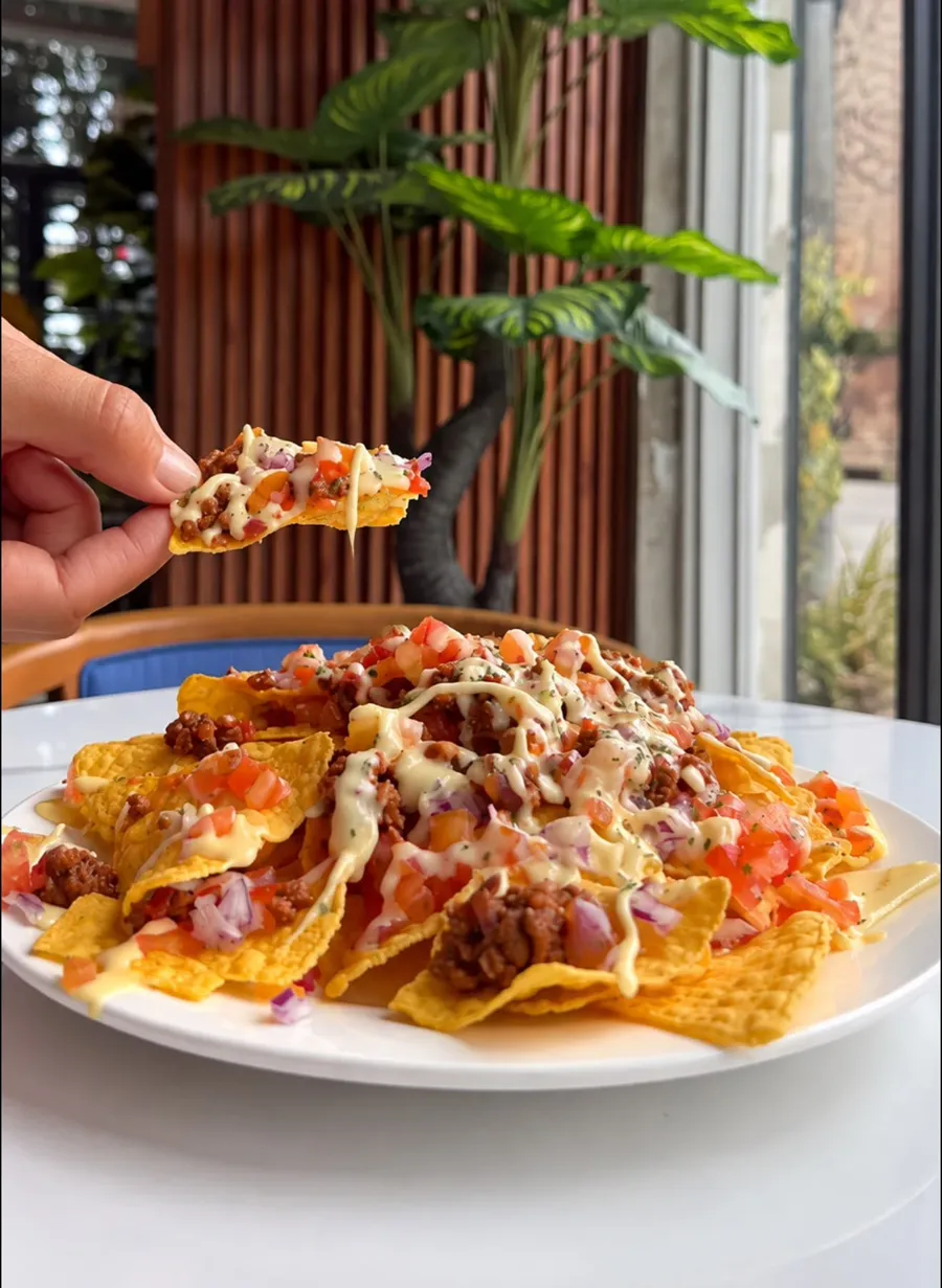 Loaded nachos, a chip lifted from the plate